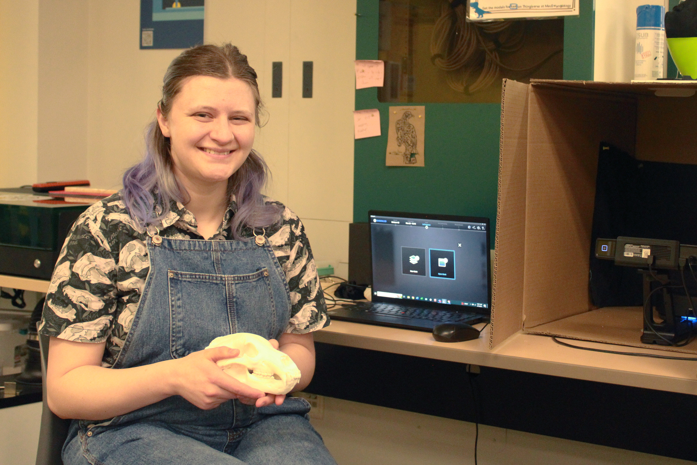 Gillian Halliday holds a half-scale print of a polar bear skull beside the 3D scanner in the Makerspace.